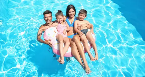 Famille dans une bouée géante dans la piscine du village vacances France VTF, moment joyeux en vacances tout compris