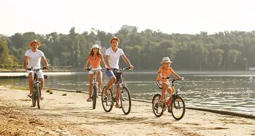 Famille en balade à vélo au bord d’un lac, moment d’activités nature en village vacances France