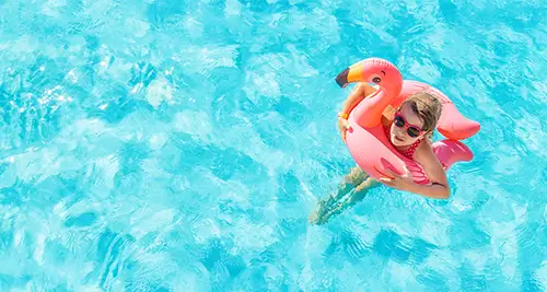 Petite fille flottant dans une bouée dans une piscine en été, pendant les vacances scolaires en village de vacances France
